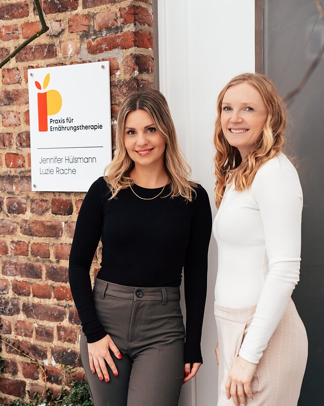 Luzie Rache und Jennifer Hülsmann vor dem Schild ihrer Praxis für Ernährungstherapie